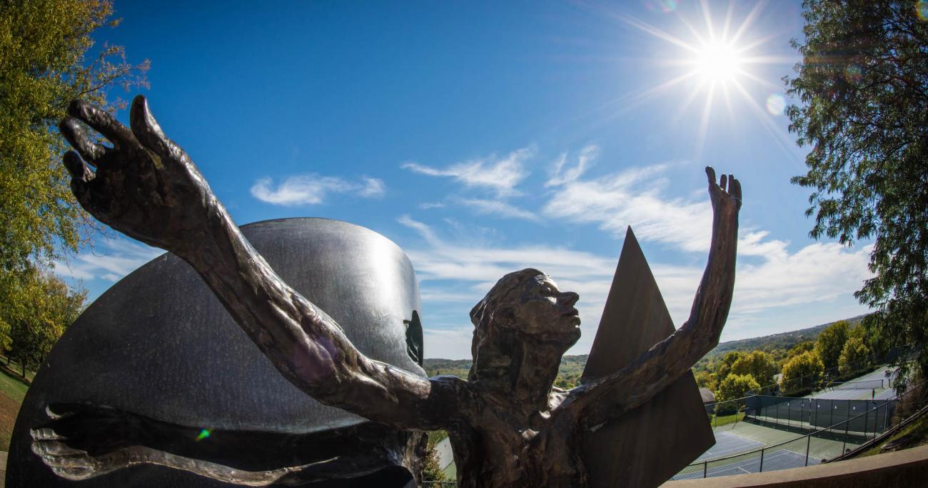 a Granlund sculpture of a woman-butterfly shown reaching toward a sunburst in a blue sky.