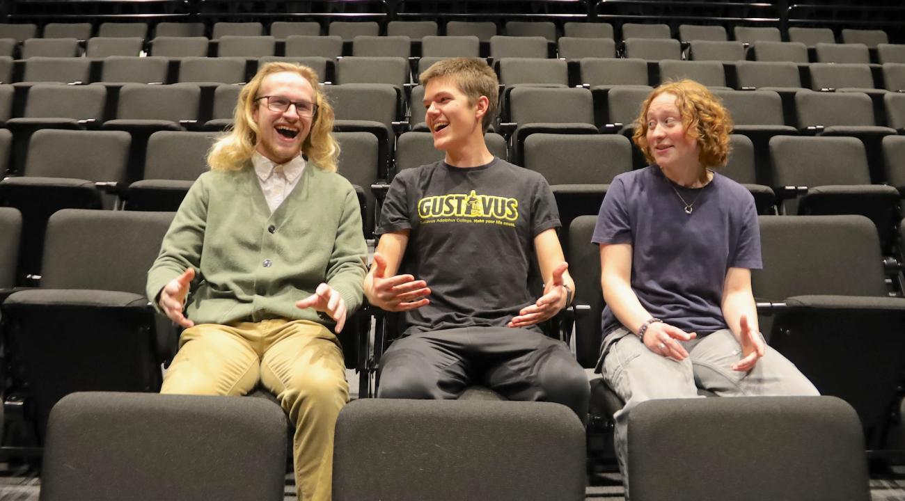 Three college students laughing in a theater.