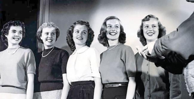 Five college-aged women smile at something off camera in 1949. 