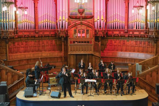 A large jazz ensemble plays in a beautiful concert hall. 