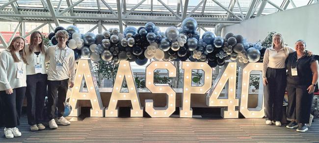 Gusties stading around large letters reading AASP40