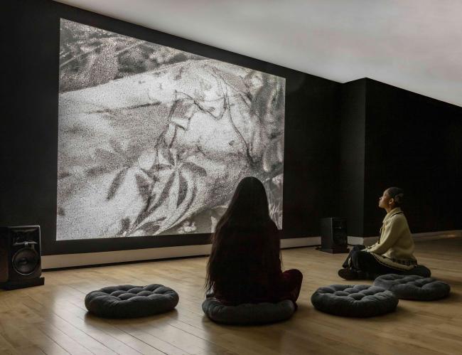 Two people sitting on floor pillows looking at black and white artwork