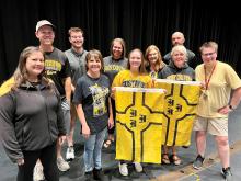 Several teachers wearing Gustavus Adolphus College gear gather with Gustavus flags