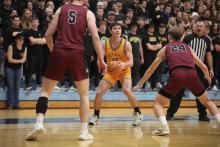 A Gustavus college basketball players frames up a shot surrounded by the opposing team. 