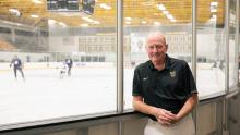 Mike Caroll standing beside the Gustavus hockey rink