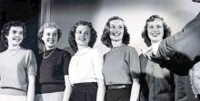 Five college-aged women smile at something off camera in 1949. 