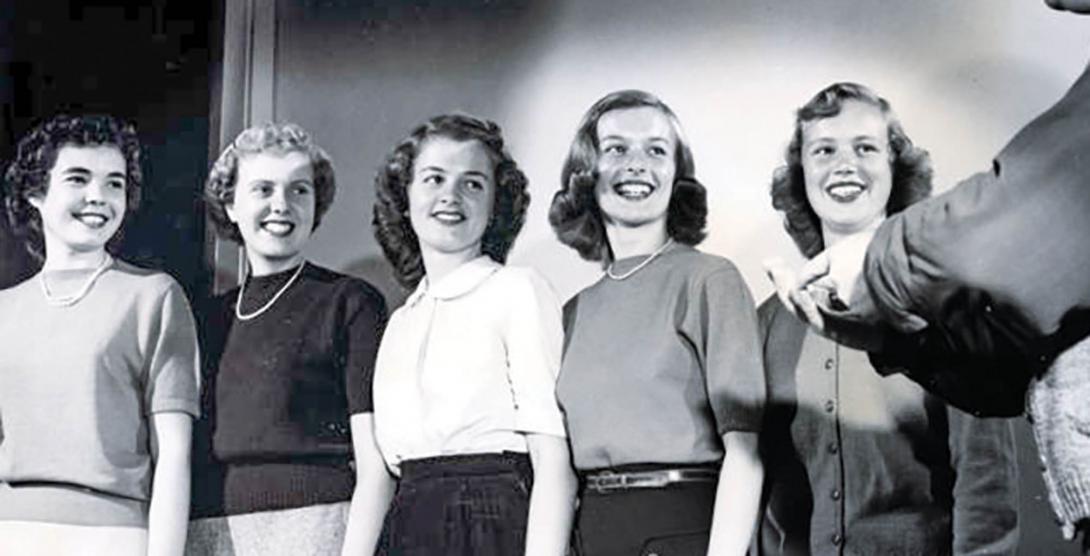 Five college-aged women smile at something off camera in 1949. 