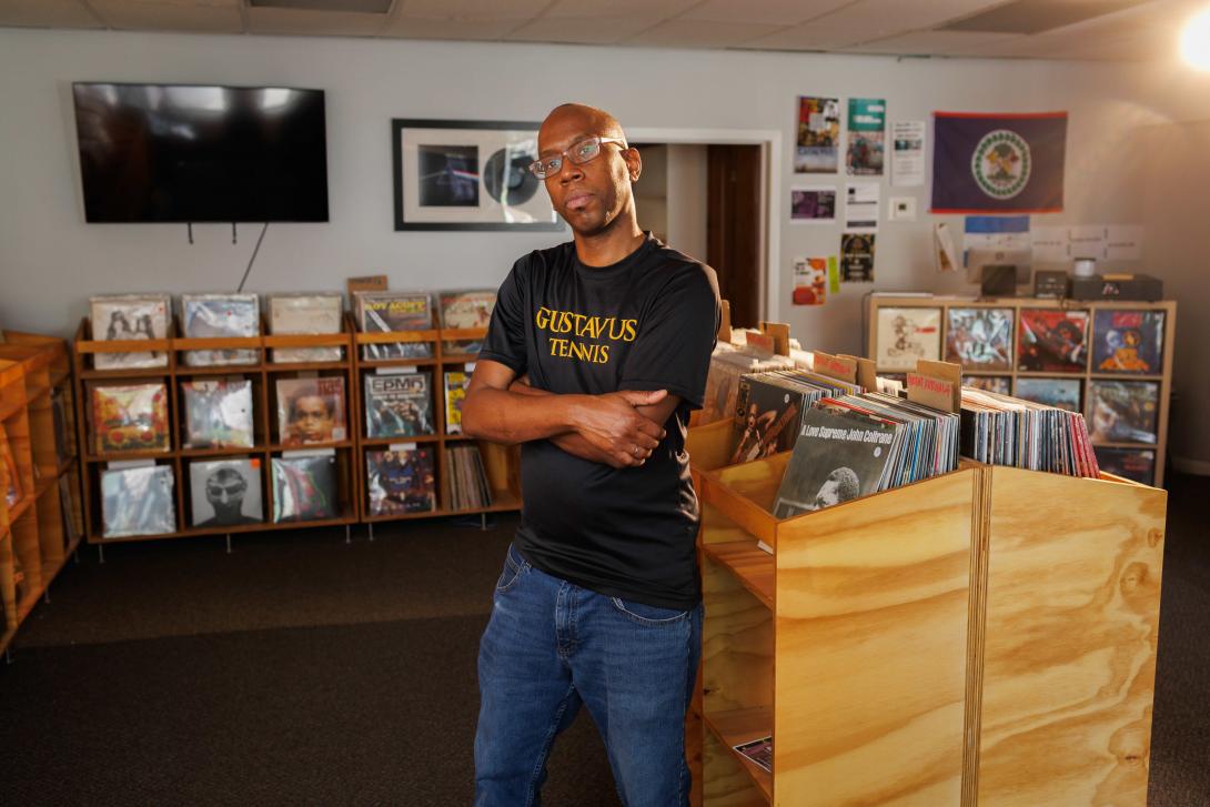 Professor in record store standing in front of record shelf. 