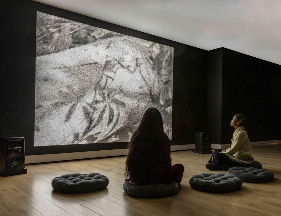 Two people sitting on floor pillows looking at black and white artwork